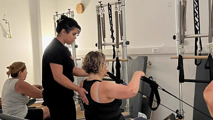 Professora do Shala a corrigir a postura de uma aluna no Reformer
